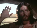 Jesus raising his hand in front of an arched window.